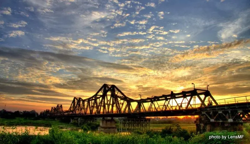 Khung cảnh ăn đêm Hà Nội nhộn nhịp với nhiều người ngồi ăn trên vỉa hè, ánh đèn vàng tạo không khí ấm cúng, phản ánh văn hóa ẩm thực đêm đặc trưng.